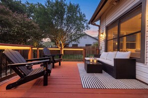 A deck with outdoor furniture, a railing, and a house in the background. - Casa Vista  Designer Home Pool Sleeps 16 (San Antonio)