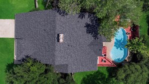 Una propiedad residencial con piscina, terraza cubierta y un amplio césped.