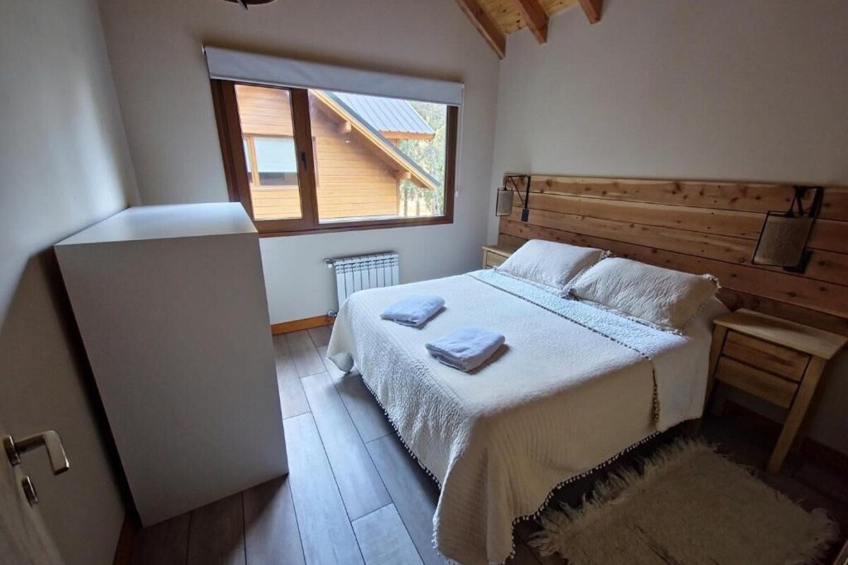 Ein Schlafzimmer mit einem Bett, einem Nachttisch, einem Fenster und einer Heizung.