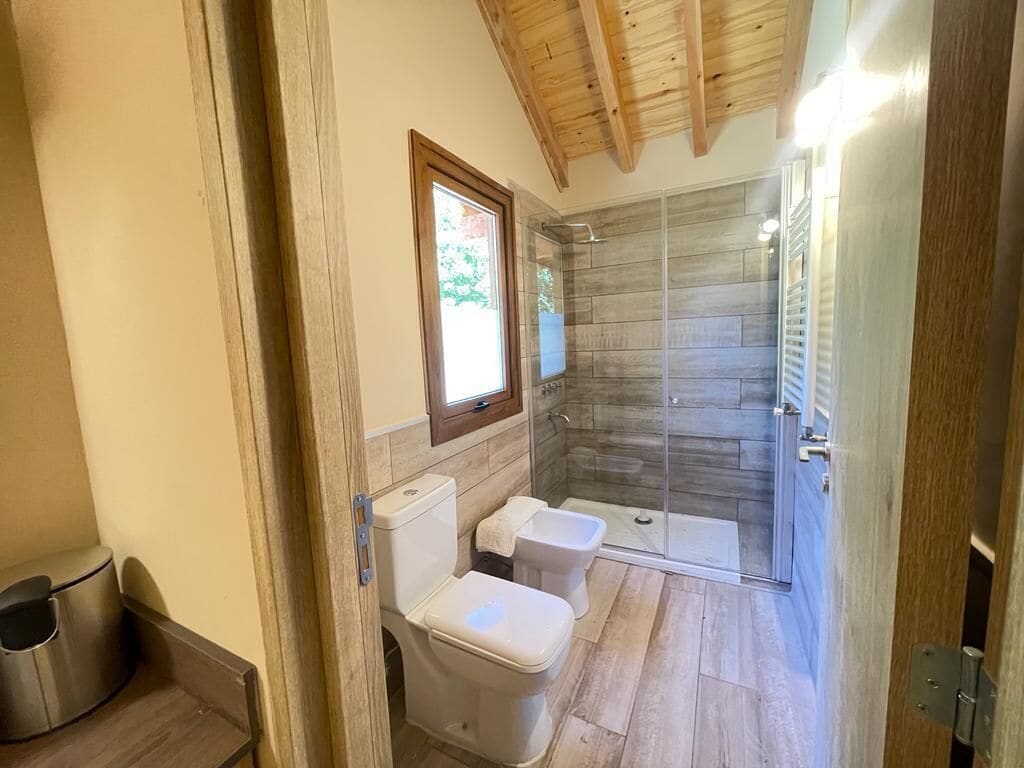 Casa de banho com duas sanitas, chuveiro e janela.