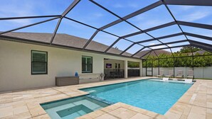 Ein Schwimmbecken mit freiem Blick zum Himmel, umgeben von einer überdachten Terrasse mit Stühlen und einer kleinen Sitzecke.
