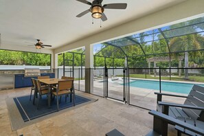 Un espace extérieur abrité comprenant une piscine, une table à manger, des chaises et un barbecue.