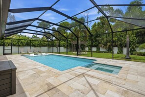 A swimming pool with a covered area, surrounded by a white fence, and a patio with chairs. - Kid-Friendly Bonita Home With Private Pool & Spa (Bonita Springs)