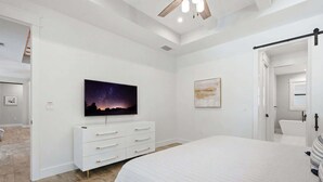 Ein Schlafzimmer mit einem Bett, einem Schminktisch, einem Gemälde und einem Deckenventilator.