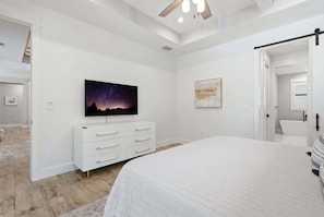 Ein Schlafzimmer mit einem Bett, einem Schminktisch, einem Gemälde und einem Deckenventilator.