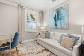 A modern living room with a sofa, a desk, and a large abstract painting. - Kid-Friendly Bonita Home With Private Pool & Spa (Bonita Springs)