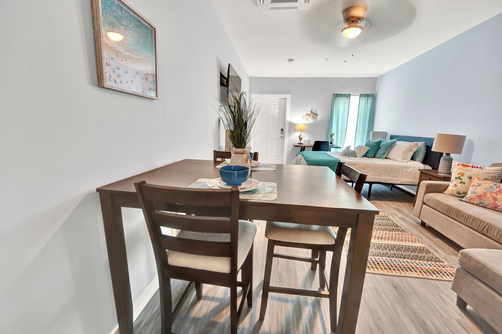 A modern living room with a dining area, featuring a sofa, a bed, and a table with chairs.