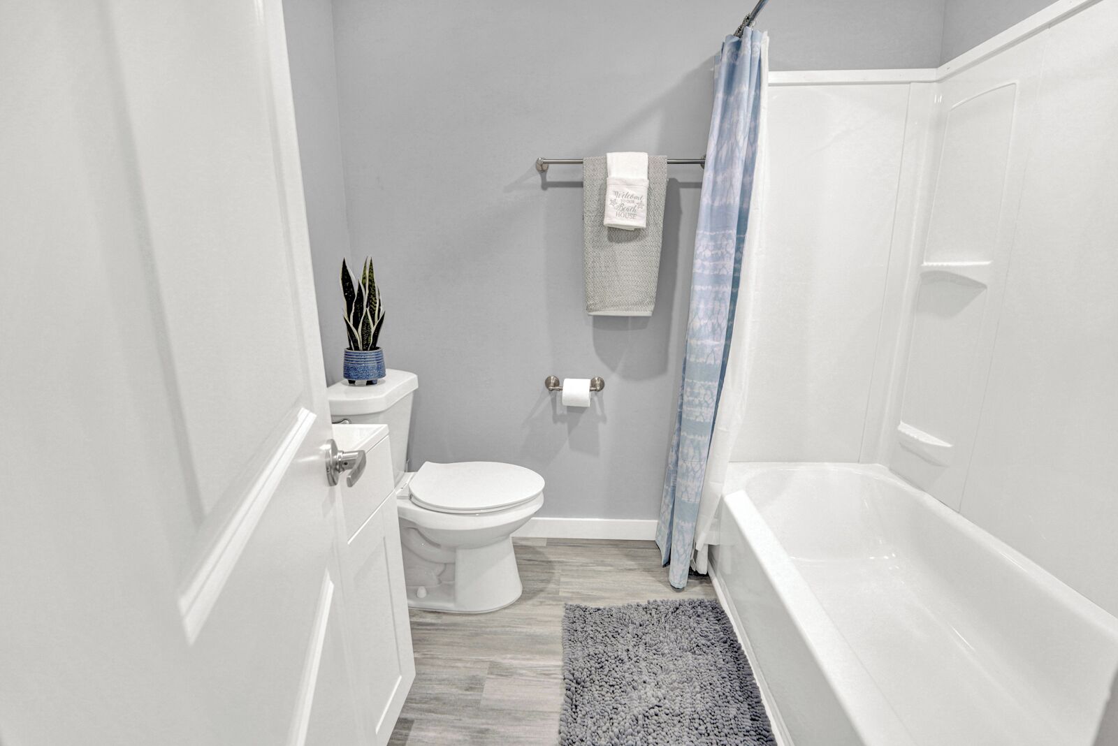A bathroom with a toilet, a towel rack, a shower curtain, and a bathtub.