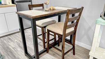 Une table à manger avec des chaises, un coin cuisine avec des placards et un réfrigérateur.