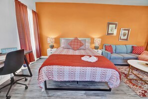 Una habitación de hotel con cama, escritorio, silla, sofá y mesa de centro.