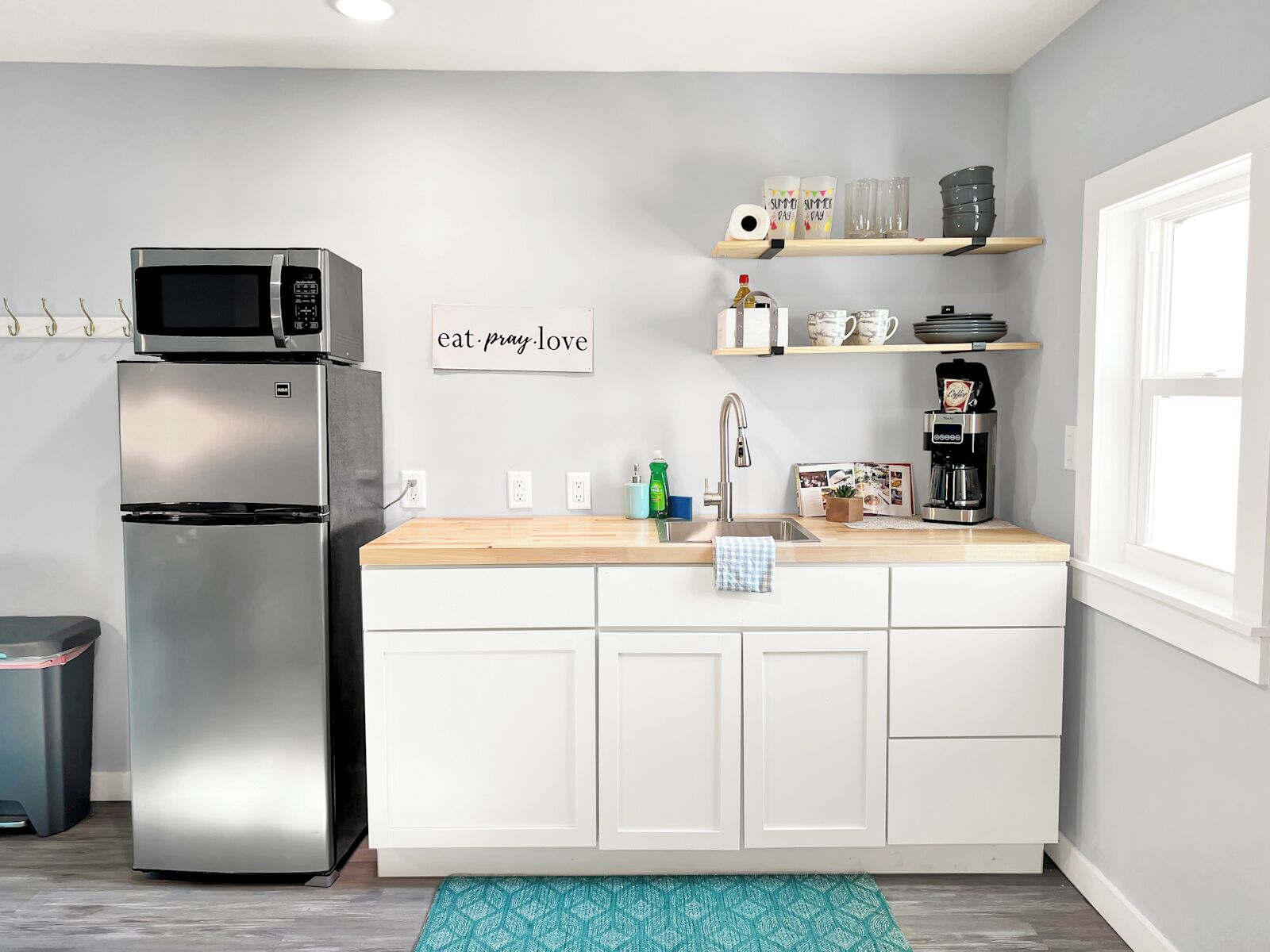 A modern kitchen with a stainless steel refrigerator, a microwave, a sink with a faucet, and a countertop with various items.