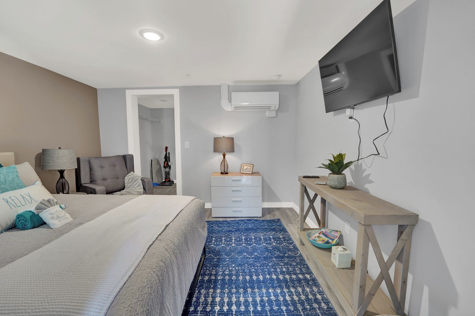 A modern bedroom with a bed, bedside tables, a TV, and a blue patterned rug.