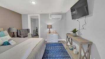 A modern bedroom with a bed, bedside tables, a TV, and a blue patterned rug.