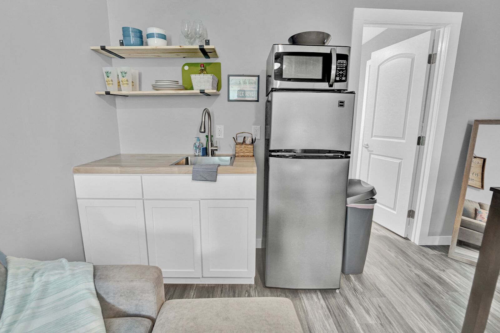 A compact kitchen with a built-in microwave and refrigerator, a wooden countertop, and a sink.