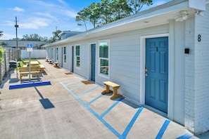 A row of single-story motel rooms with blue doors, a parking lot with blue lines, and a sign indicating handicapped accessibility. - Seaside Escape FL (Fort Walton Beach)