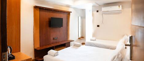Habitación de hotel con cama de madera, televisor de pantalla plana, ventilador de techo y aire acondicionado.
