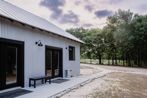 A building with a corrugated metal roof, large windows, and a bench outside. - Limestone Fields (Jewett)