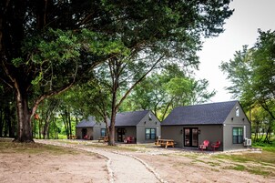 Una cabaña de estilo rústico con un sendero de tierra que conduce a ella, rodeada de árboles.