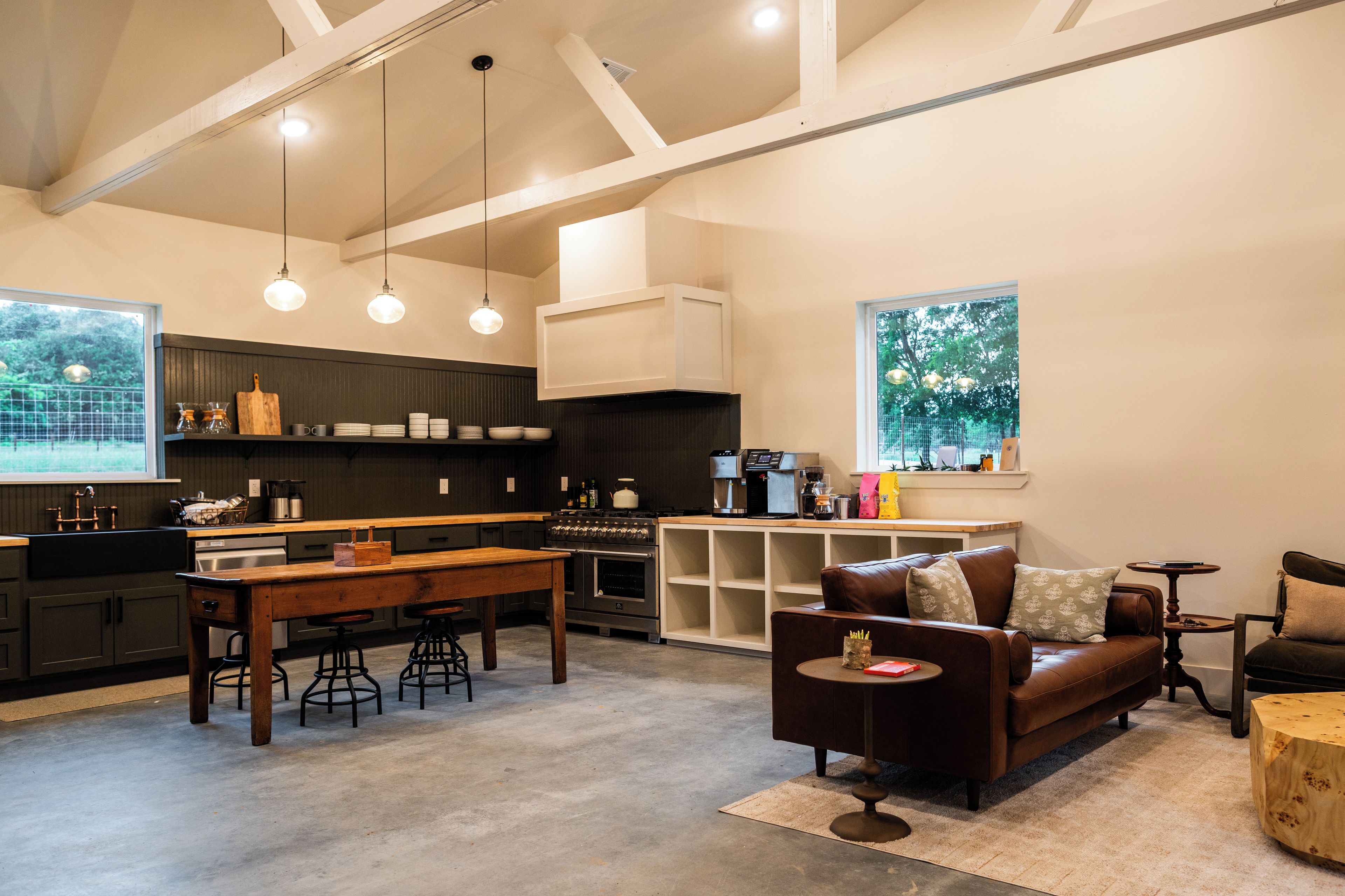 A modern kitchen with a central island, bar stools, and a dining table.