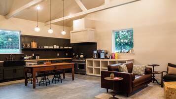 A modern kitchen with a central island, bar stools, and a dining table.