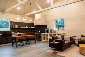 A modern kitchen with a central island, bar stools, and a dining table. - Limestone Fields (Jewett)