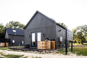 A modern building with a dark exterior, a front door, and a wooden barrel outside.
