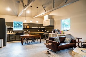 A modern kitchen with a dining area, a sofa, and a coffee table. - Limestone Fields (Jewett)