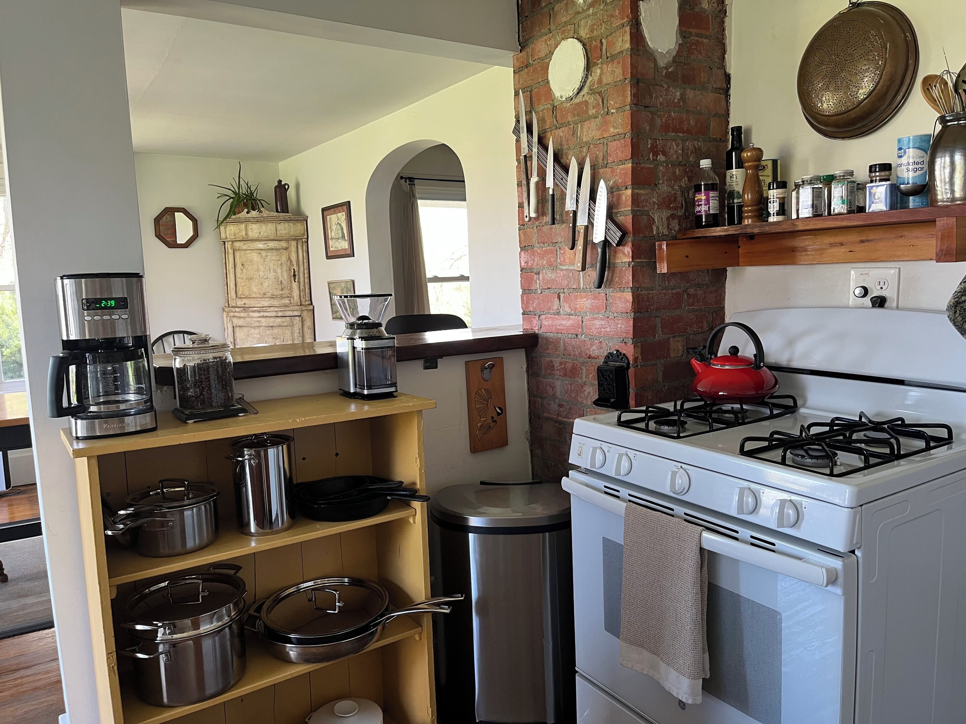 A kitchen with a gas stove, coffee maker, and various kitchen utensils.