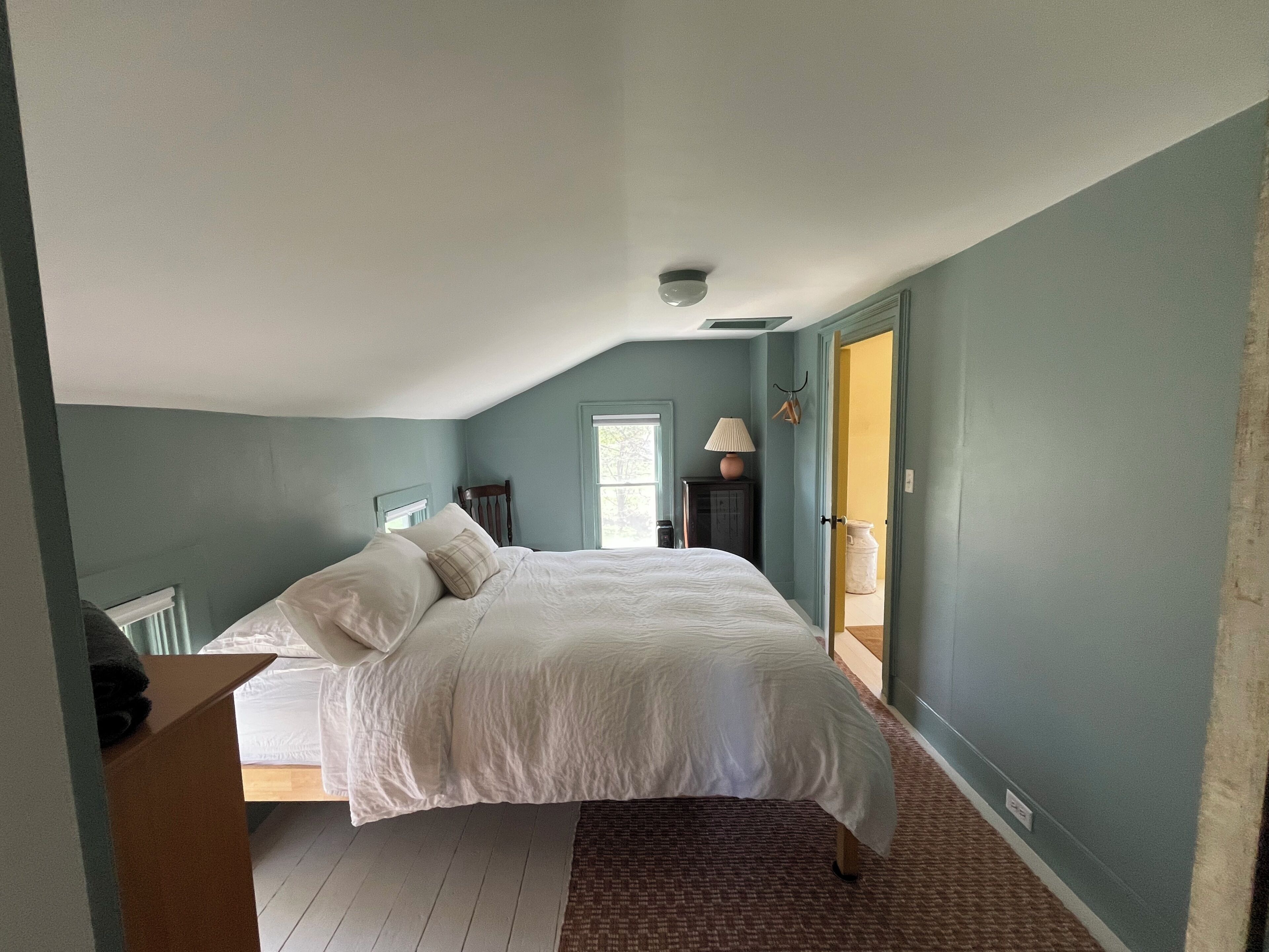 A bedroom with a bed, a nightstand, a lamp, and a window.