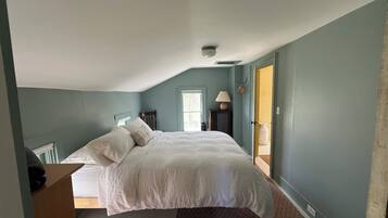 A bedroom with a bed, a nightstand, a lamp, and a window.