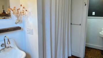 A bathroom with a white sink, a shower curtain, and a wooden floor.