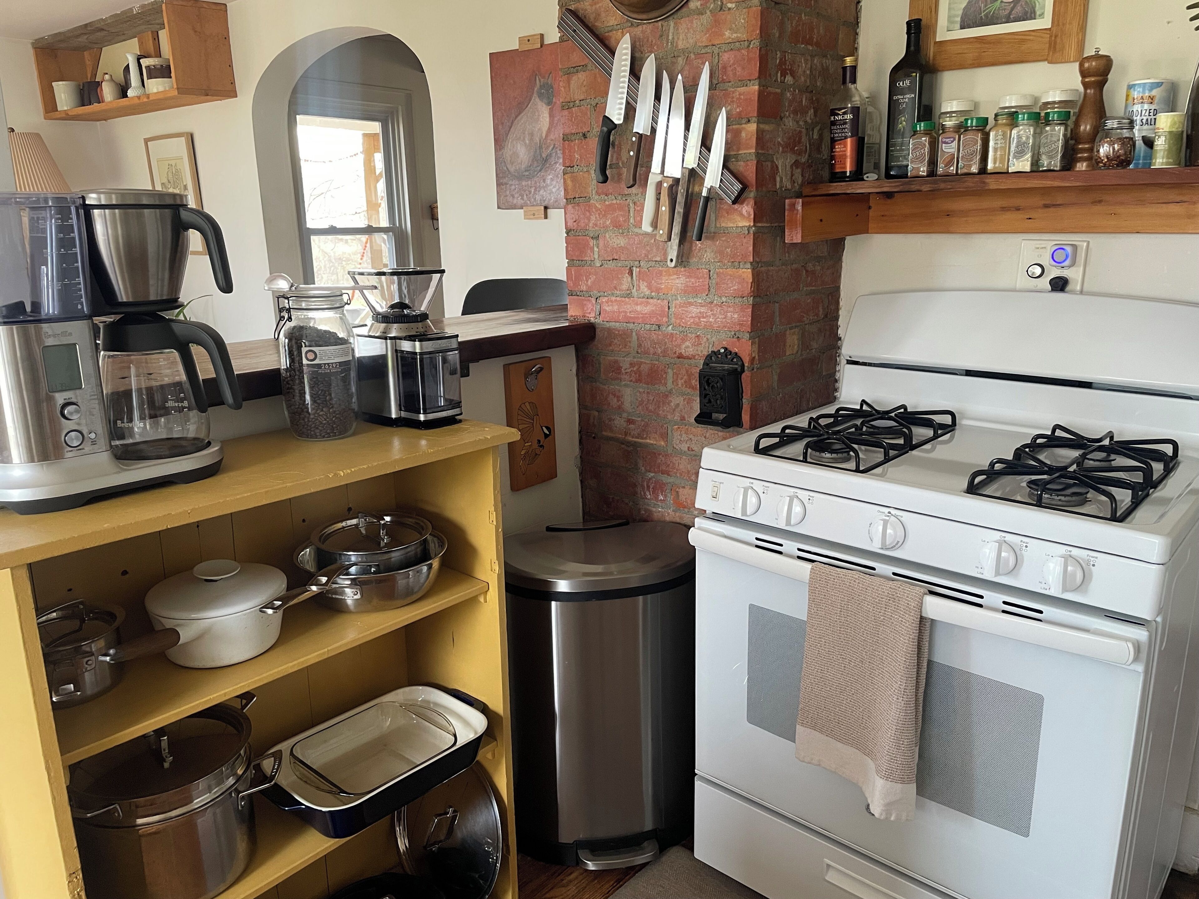 A kitchen with a stove, oven, coffee maker, and various kitchen utensils.