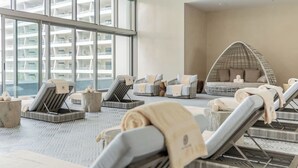 Moderni spa-alue, jossa on aurinkotuoleja, riipputuoli ja näkymä korkeaan rakennukseen.