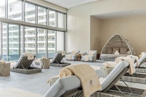 A modern spa area with loungers, a hanging chair, and a view of a high-rise building. - Cozy 1-bedroom condo with AC in awesome Q.R. location (Q.R.)
