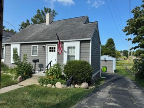 A residential house with a front porch, a mailbox, and a small garden with flowers and rocks. - 3-bedroom bungalow in peaceful Fenton in the Shiawassee River! (Fenton)
