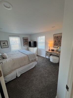 A bedroom with a bed, a desk, a television, and artwork on the walls. - 3-bedroom bungalow in peaceful Fenton in the Shiawassee River! (Fenton)