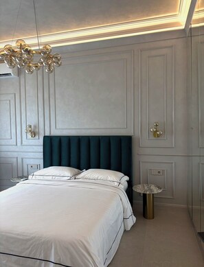 A modern bedroom with a large bed, a dark headboard, and a unique chandelier.