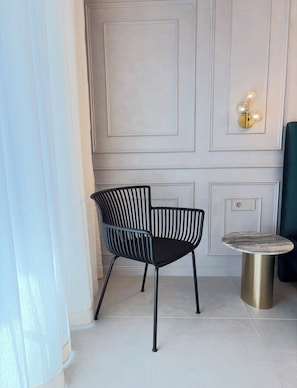 A modern interior with a black chair, a round table, and a wall-mounted light fixture. - Stylish beach apartment near Kavatsi Beach, Sozopol (Sozopol)