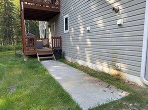 A residential property with a covered porch, a concrete pathway leading to the entrance, and a small outdoor seating area. - Comfortable Apartment, Extended Stays Welcome (North Pole)