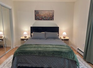 A bedroom with a bed, bedside lamps, a mirror, and a painting on the wall. - Comfortable Apartment, Extended Stays Welcome (North Pole)
