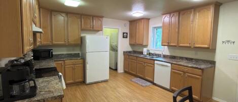 A kitchen with wooden cabinets, a refrigerator, a coffee maker, and a dining table.