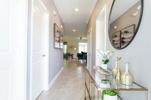 A hallway with a glass console table, decorative vases, and a mirror. - Magical 5BR Villa  Game Room & Pool  5mi to Disney (Kissimmee)