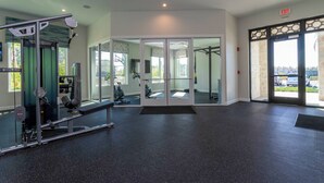 Un gimnasio con equipo de ejercicio, un espejo grande y una puerta de salida.