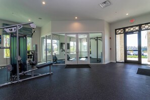 Ein Fitnessraum mit Trainingsgeräten, einer Spiegelwand und einer Ausgangstür.