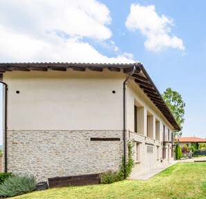 Un edificio con fachada de piedra, techo plano y galería cubierta.