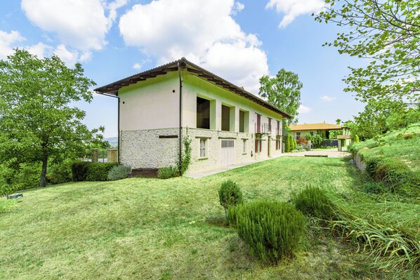 A two-story house with a stone facade, a flat roof, and a well-maintained lawn.
