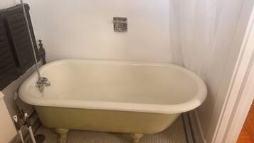 A bathroom with a freestanding bathtub, a toilet, and a shower area.