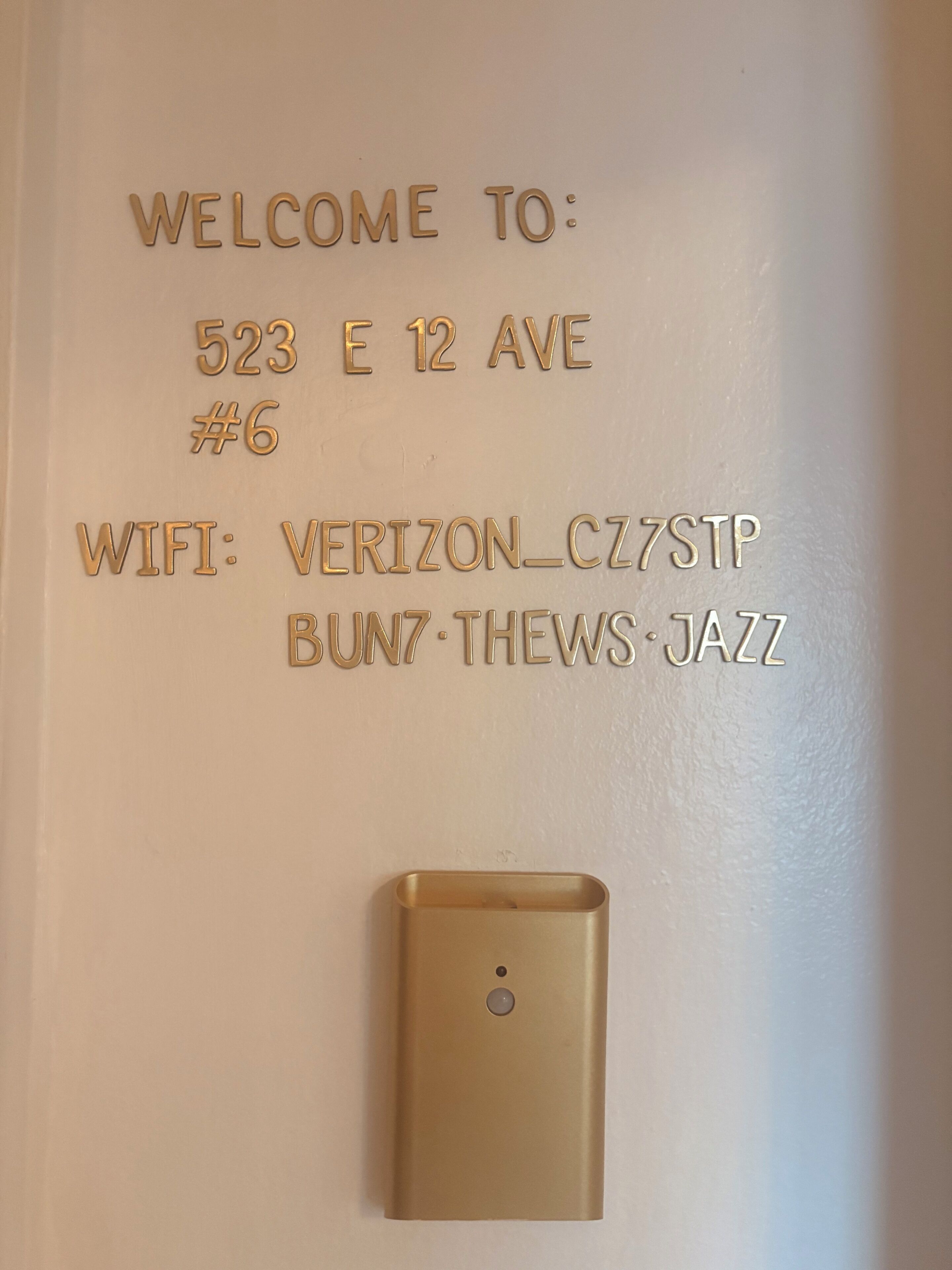 A wall with embossed text indicating a welcome message, address, and WiFi details.