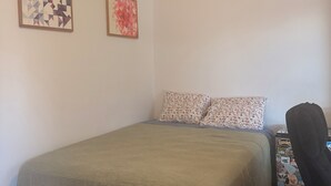 A room with a bed, two wall-mounted artworks, a ceiling light, and a chair with stickers. - Quiet central studio apartment in the Capital Hill neighborhood of Denver (Denver)