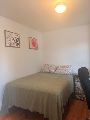 A room with a bed, two wall-mounted artworks, a ceiling light, and a chair with stickers. - Quiet central studio apartment in the Capital Hill neighborhood of Denver (Denver)